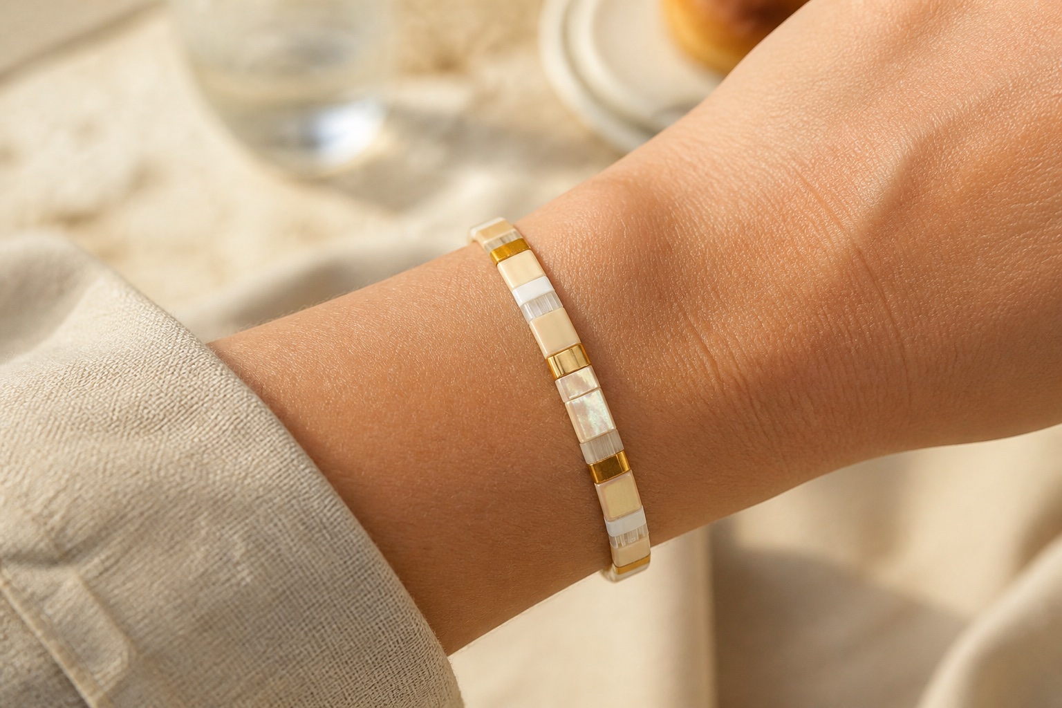 Editorial concept of a close wrist wearing a snug pearl and gold tile bracelet