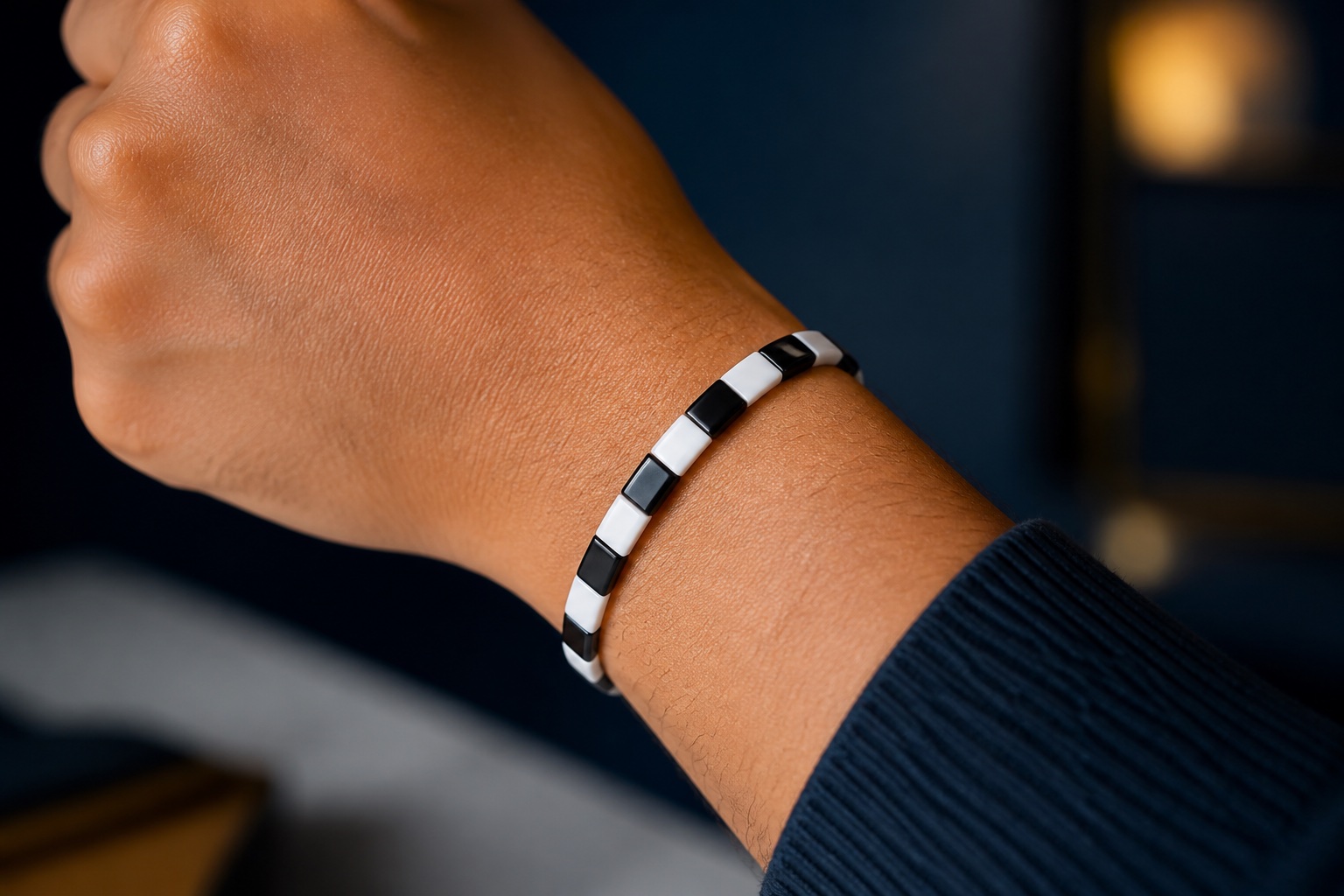 Editorial concept of a close wrist wearing a snug black and white tile bracelet